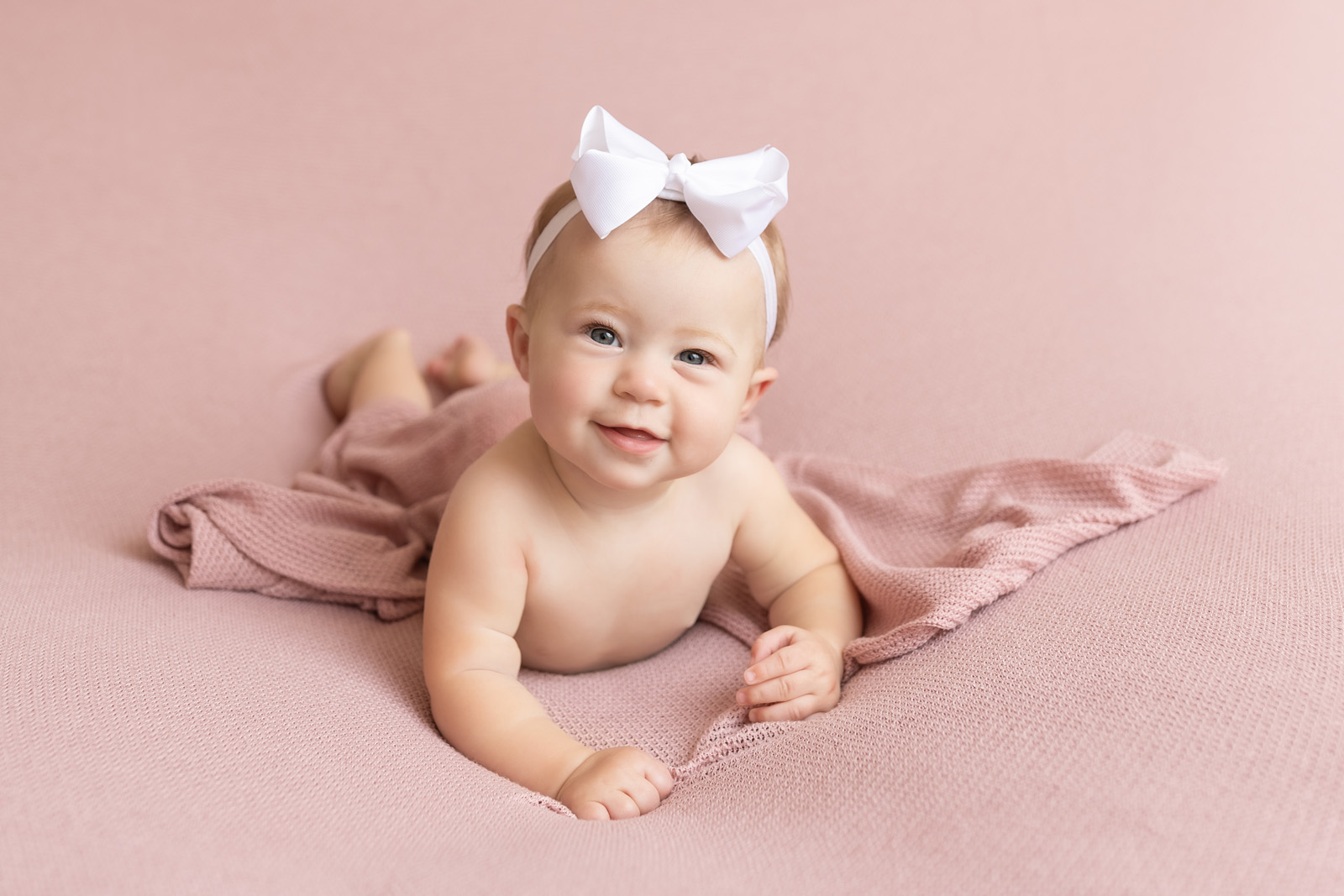 Baby milestone sessions for 6 month old girl smiling with pink blanket