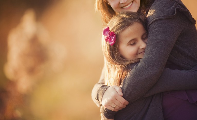 backlit photo of mom hugging daughter by Julia Woods