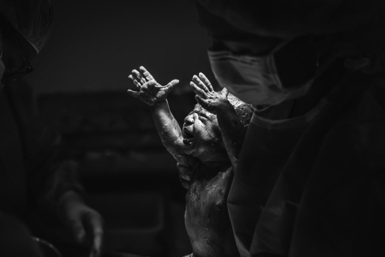 Newborn baby reaches towards light