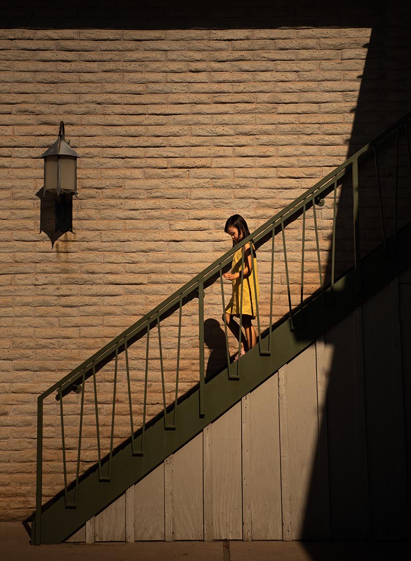 girl walking down stairs in dramatic light