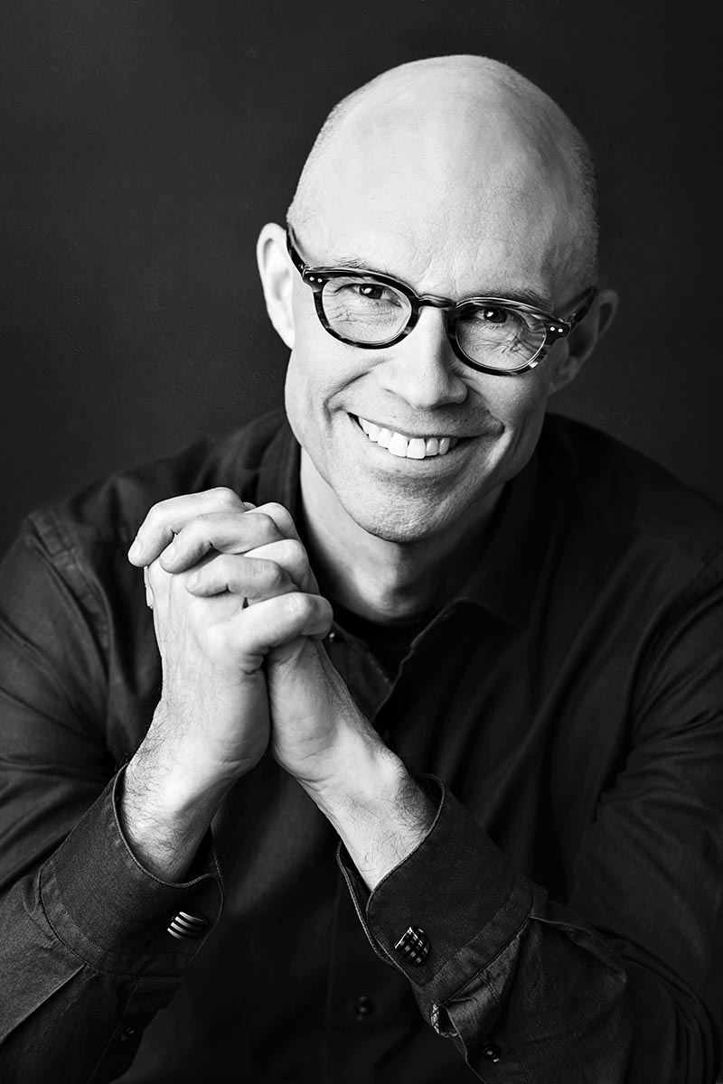 Headshot of a man with his hands folded.