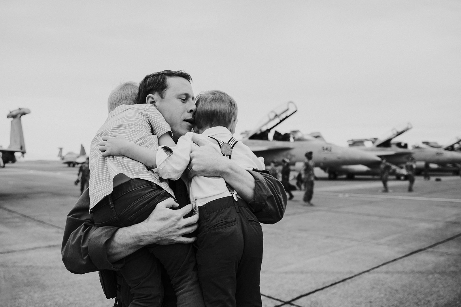 man-holds-and-hugs-sons-on-flight-line-at-homecoming-by-Kara-Chappell