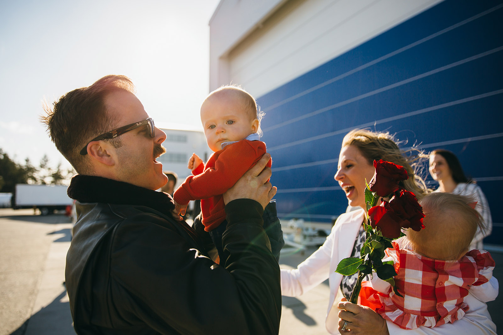 man-holds-baby-boy-while-family-cheers-at-military-homecoming-by-Kara-Chappell Photographing a military homecoming - tips for photographers