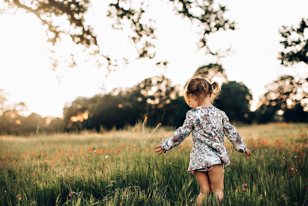 photo of girl in a flower dress walking through a field by Winnie Bruce