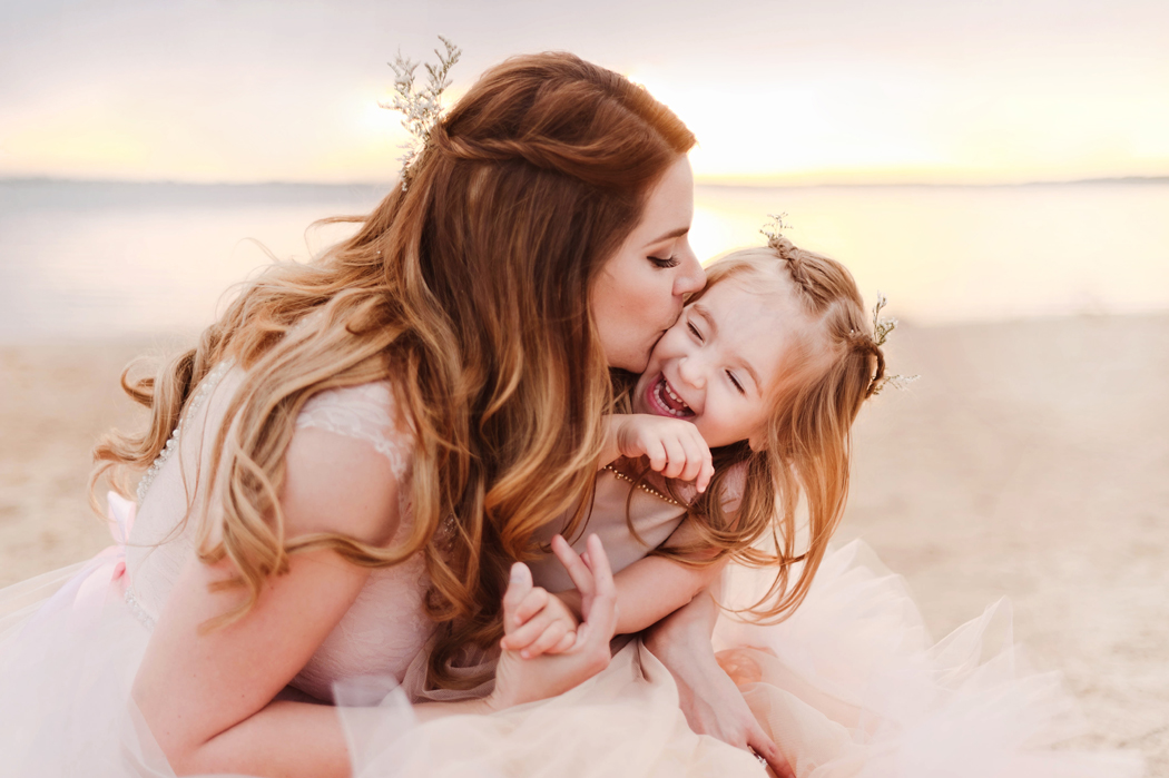 photo of mom giving daughter a kiss on the beach by Woodsy Wonders Photography