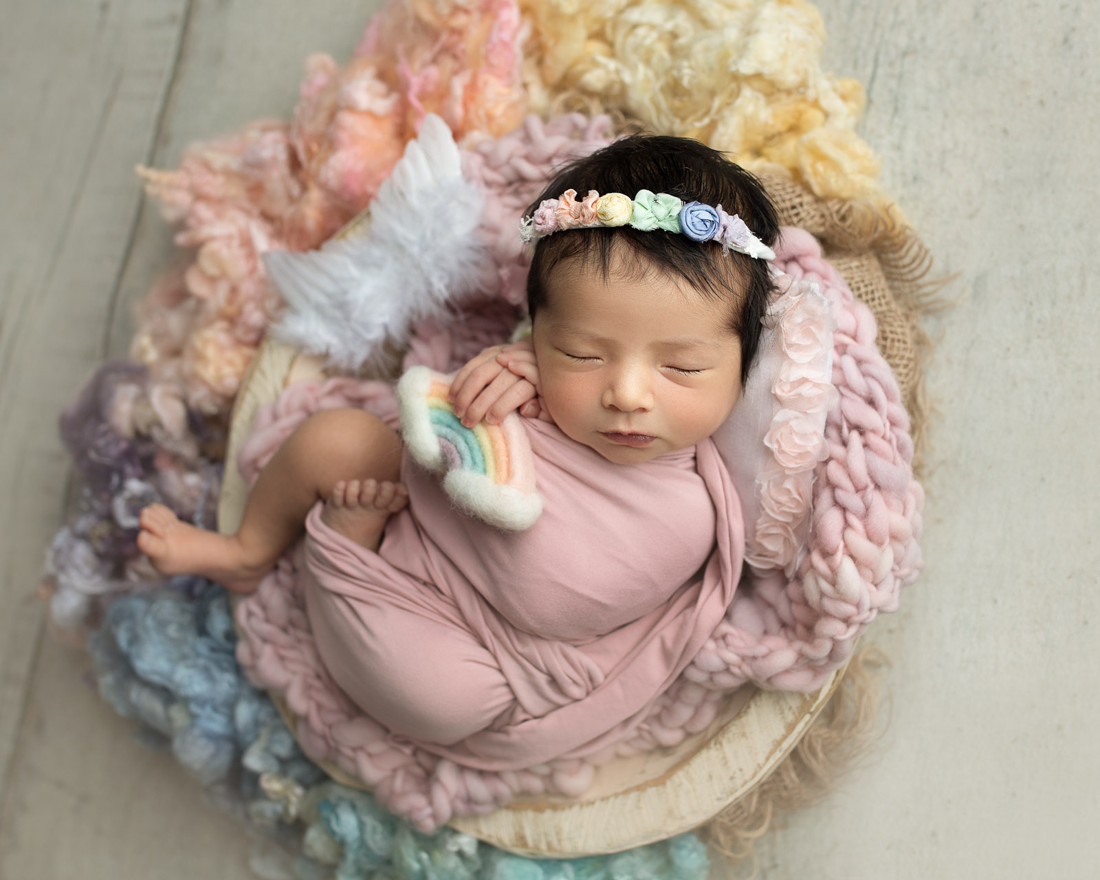 rainbow-baby-newborn-photography-crystal-reddick Newborn baby posed in a basket with rainbow