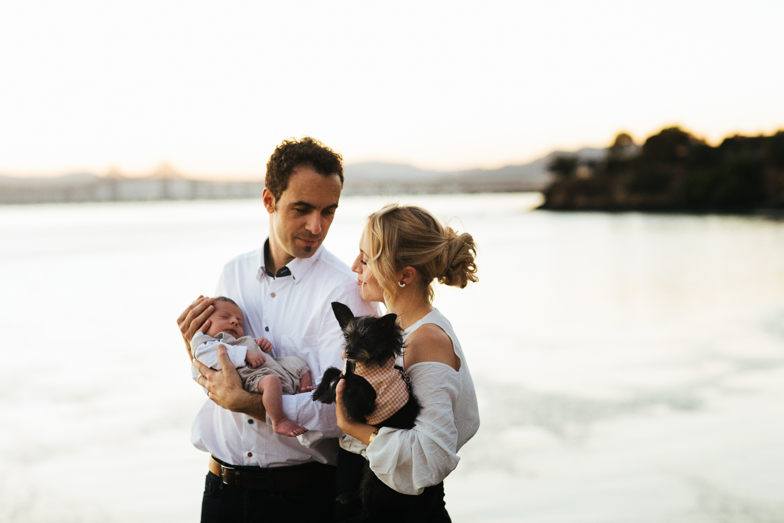 Travel photo of a couple holding a newborn and a dog in Point Richmond, California