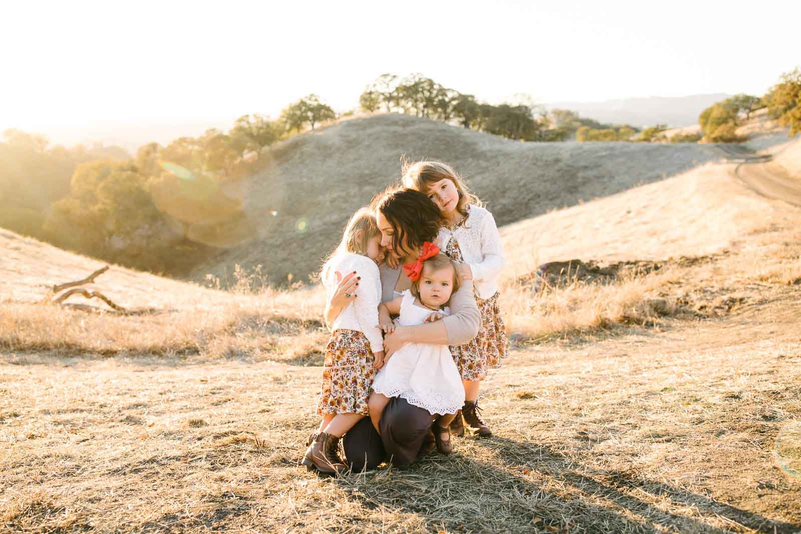A photography travel session in Walnut Creek, a mom hugs her three girls