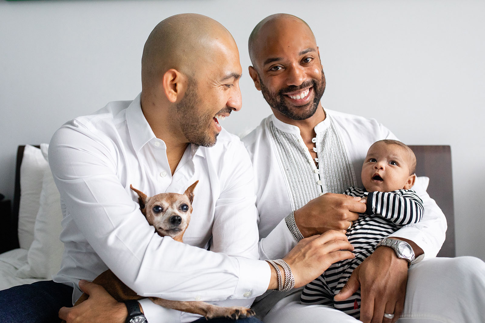 Smiling fathers hold newborn during pandemic photo session