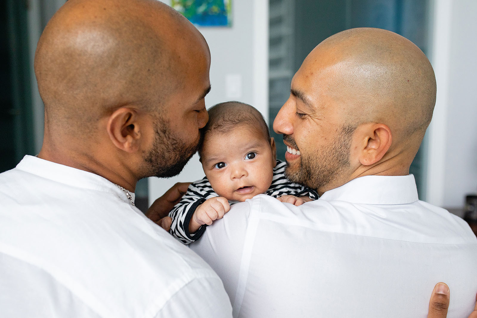 Dads hold their baby during newborn photo session
