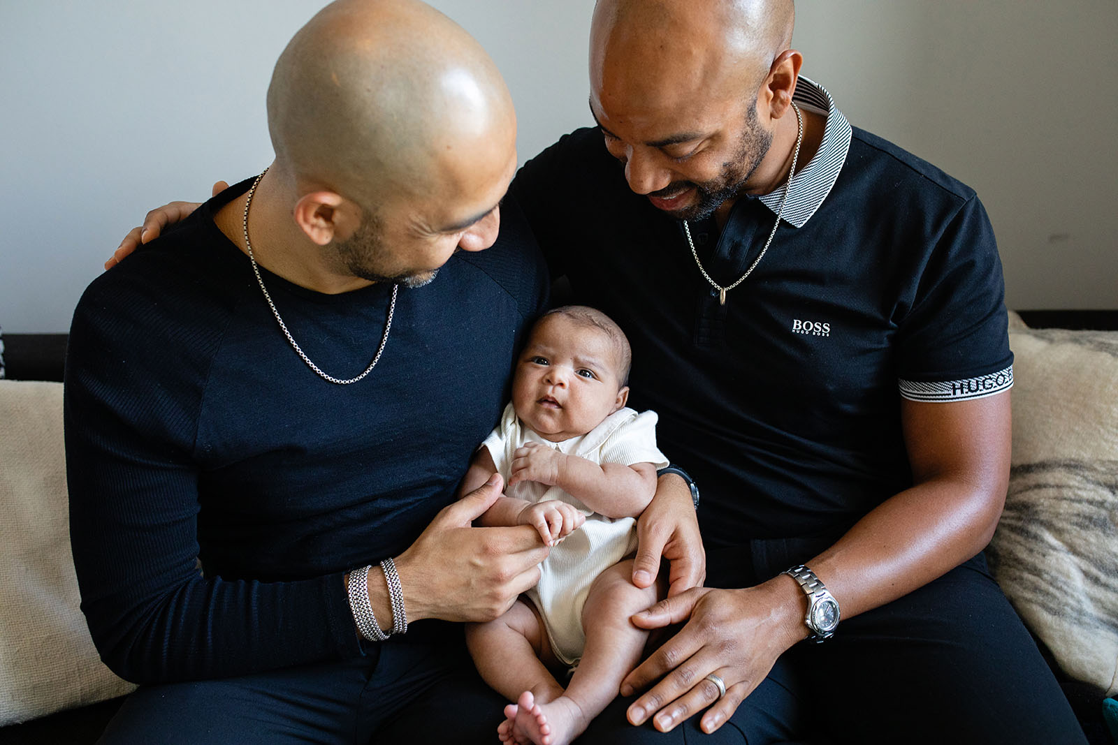 Two fathers hold their newborn baby girl during covid safe photo session in Miami